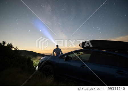 Silhouette of man at offroad car with head flashlight on background of very beautiful night starry sky after sunset. Freedom and travel by car concept 99331240
