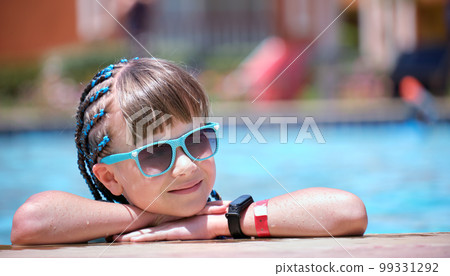 Portrait of happy child girl relaxing on swimming pool side on sunny summer day during tropical holidays Portrait of happy child girl relaxing on swimming pool side on sunny summer day during tropical holidays 99331292