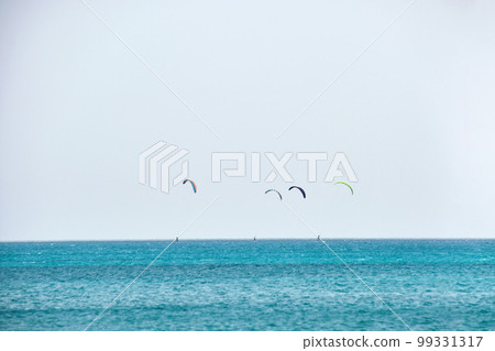 People sportsmen windsurfing and kite surfing in blue ocean water. Summer extreme exotic sport concept 99331317