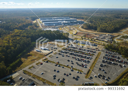 Many associate cars parked on big parking lot in front of industrial factory building. Manufactoring and global industry concept 99331692