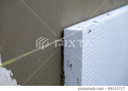 Installation of styrofoam insulation sheets on house facade wall for thermal protection. 99331727