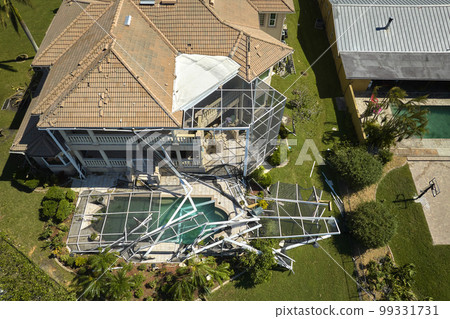 Hurricane Ian destroyed swimming pool lanai enclosure on house yard in Florida residential area. Natural disaster and its consequences Hurricane Ian destroyed swimming pool lanai enclosure on house yard in Florida residential area. Natural disaster and its consequences 99331731