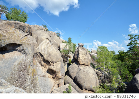 Huge rocky boulder formations high in mountains with growing trees on summer sunny day Huge rocky boulder formations high in mountains with growing trees on summer sunny day 99331740
