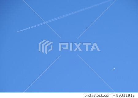 Distant passenger jet plane flying on high altitude on clear blue sky leaving white smoke trace of contrail behind. Air transportation concept. 99331912