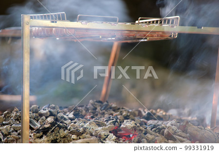 Delicious grilled meat sizzling over the burning coals on barbecue outdoors 99331919