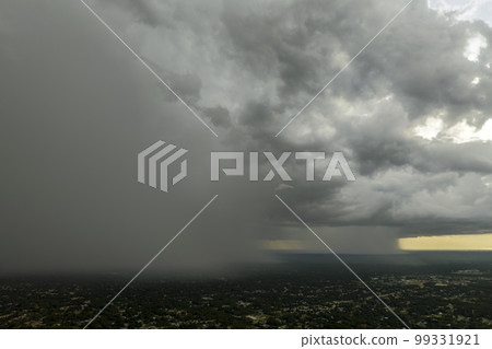 Dark stormy clouds forming on gloomy sky during heavy rainfall season over suburban town area 99331921