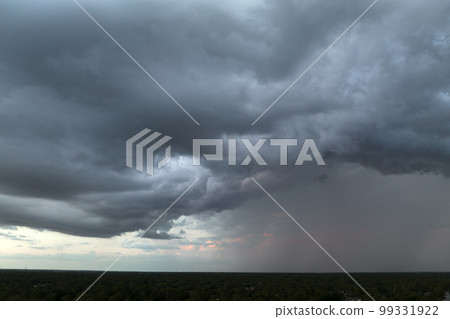 Dark stormy clouds forming on gloomy sky before heavy rainfall over suburban town area Dark stormy clouds forming on gloomy sky before heavy rainfall over suburban town area 99331922
