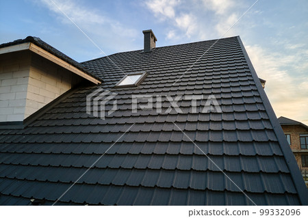 Closeup of house roof top covered with metallic shingles.Tiled covering of building 99332096
