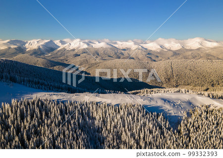 Aerial view of winter landscape with mountain hills covered with evergreen pine forest after heavy snowfall on cold bright day. Aerial view of winter landscape with mountain hills covered with evergreen pine forest after heavy snowfall on cold bright day. 99332393