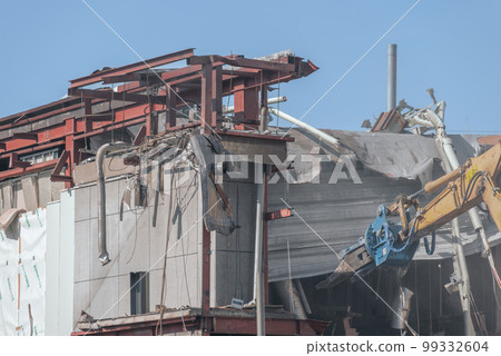 Heavy machinery dismantling the roof of a store 99332604