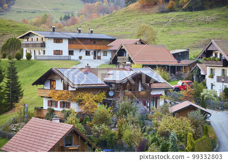 Village in the Bavarian Alps, houses, trees and mountain slopes in autumn. 99332803