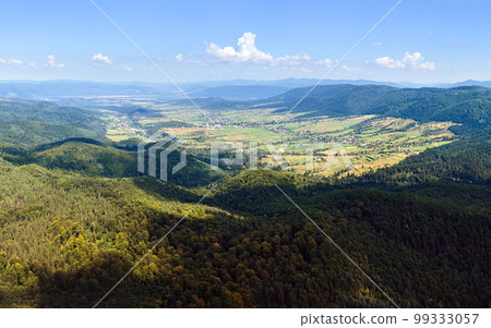 Aerial view of mountain hills covered with dense green lush woods on bright summer day. Aerial view of mountain hills covered with dense green lush woods on bright summer day. 99333057