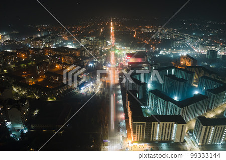 Aerial view of high rise apartment buildings and bright illuminated streets in city residential area at night. Dark urban landscape 99333144