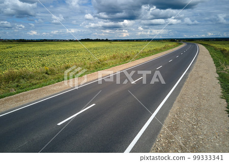 Aerial view of empty intercity road between green agricultural fields. Top view from drone of highway roadway Aerial view of empty intercity road between green agricultural fields. Top view from drone of highway roadway 99333341