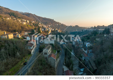 Aerial view of dense historic center of Thiers town in Puy-de-Dome department, Auvergne-Rhone-Alpes region in France. Rooftops of old buildings and narrow streets at sunset Aerial view of dense historic center of Thiers town in Puy-de-Dome department, Auvergne-Rhone-Alpes region in France. Rooftops of old buildings and narrow streets at sunset 99333357