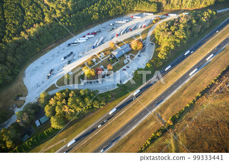 Aerial view of big rest area near busy american freeway with fast moving cars and trucks. Recreational place during interstate travel concept Aerial view of big rest area near busy american freeway with fast moving cars and trucks. Recreational place during interstate travel concept 99333441