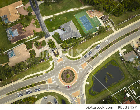 Aerial view of american suburban area with rural road roundabout intersection with moving cars traffic. Circular transportation crossroads in Florida 99333457