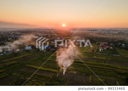 Aerial view of agricultural waste bonfires from dry grass and straw stubble burning with thick smoke polluting air during dry season on farmlands causing global warming and carcinogen fumes 99333468