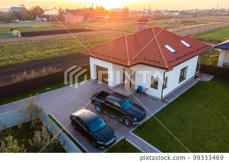 Aerial view of a private suburban house with parked cars in back yard. 99333469