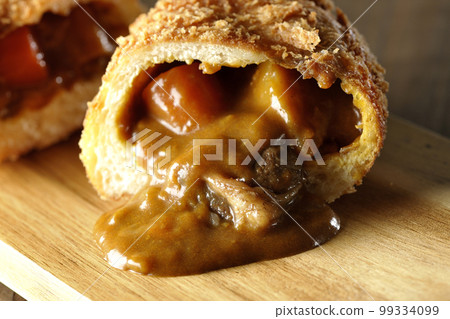 咖哩麵包配蔬菜和牛肉,在砧板上切成兩半,麵糊流出 咖哩麵包配蔬菜和牛肉,在砧板上切成兩半,麵糊流出 99334099