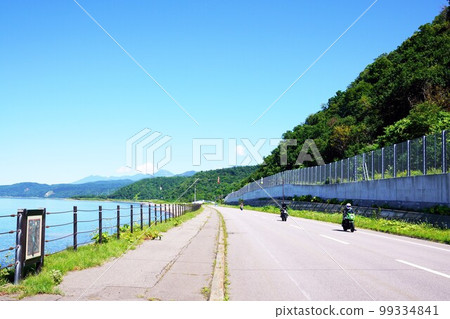Three motorcycles running with the Sea of Okhotsk and the Shiretoko mountains in the background Hokkaido Three motorcycles running with the Sea of Okhotsk and the Shiretoko mountains in the background Hokkaido 99334841
