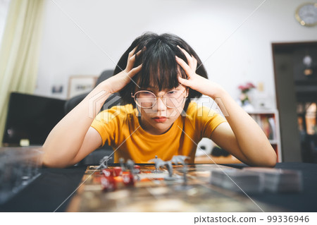 Young adult southeast asian woman playing board game on top table 99336946
