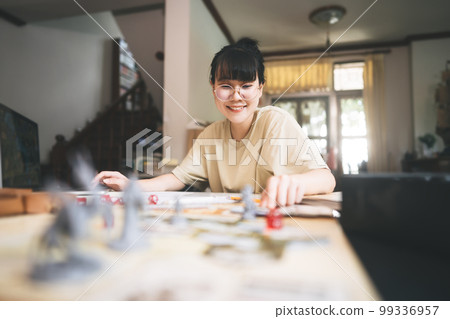 Young adult asian woman enjoying role playing tabletop storytelling and board game with miniatures Young adult asian woman enjoying role playing tabletop storytelling and board game with miniatures 99336957