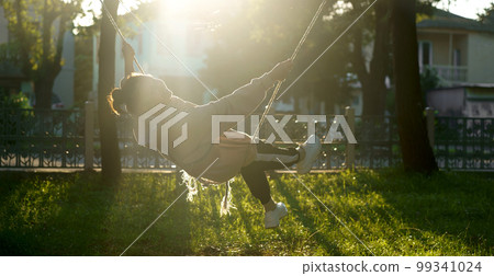 pretty woman rides on a swing near her house pretty woman rides on a swing near her house 99341024