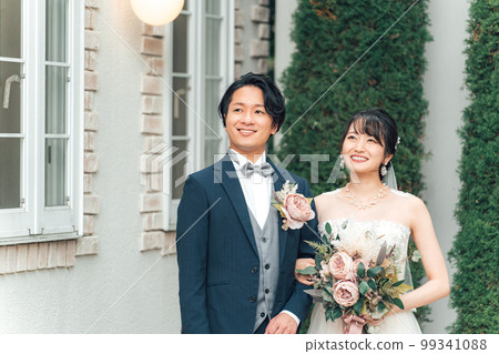 新娘和新郎在婚禮儀式（花園婚禮）的婚禮大廳的花園裡拿著花束 99341088