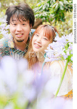 Couple smiling surrounded by purple flowers 99346205