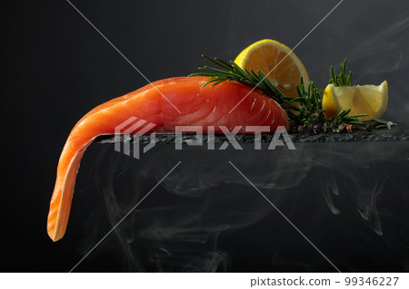 Smocked salmon with rosemary, lemon, and peppercorn on a black background. 99346227