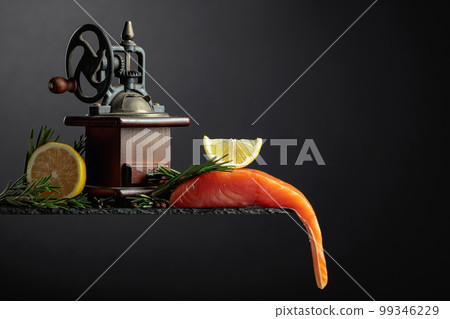 Salmon with rosemary, lemon, and peppercorn on a dark background. 99346229
