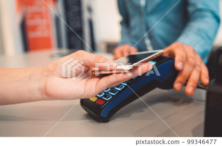 Wireless payment with a phone - Person holding a phone over the credit card reader 99346477