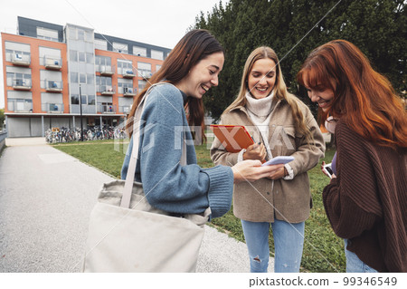 Best friends on college laughing about something while standing outside on the campus grounds 99346549
