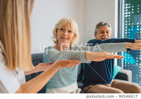 Senior couple on physiotherapy session with home caregiver Senior couple on physiotherapy session with home caregiver 99346617
