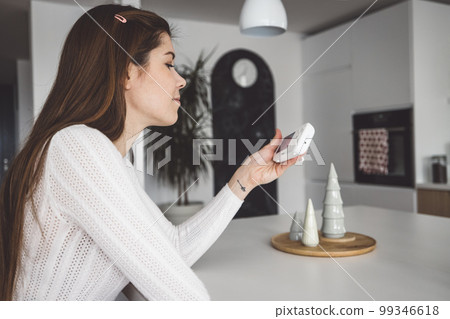 Woman sitting down at the kitchen island looking at the baby camera Woman sitting down at the kitchen island looking at the baby camera 99346618