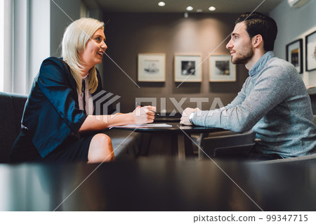 Business meeting one on one, blonde businesswoman, a lawyer, meeting with her client, young man Business meeting one on one, blonde businesswoman, a lawyer, meeting with her client, young man 99347715