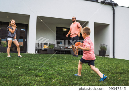 Father and his children, a girl and a boy playing on the grass with basketball 99347845
