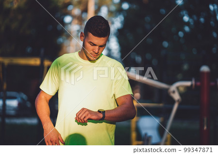 Waist au fit man looking down at his watch after a run 99347871