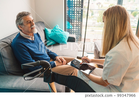 Nurse sitting on the chair across the senior man sitting on the sofa carefully listening to her  99347966