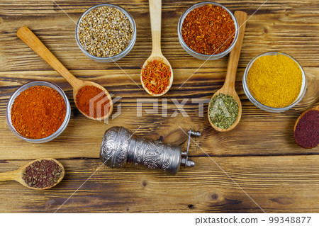 Set of different aromatic spices and spice mill on wooden table. Top view Set of different aromatic spices and spice mill on wooden table. Top view 99348877