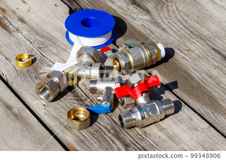 Various plumbing spare parts and sealing tape on rustic wooden background 99348906