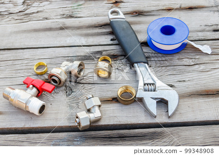 Various plumbing spare parts, sealing tape and adjustable wrench on rustic wooden background Various plumbing spare parts, sealing tape and adjustable wrench on rustic wooden background 99348908