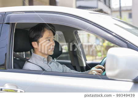 A man in his 50s driving a car 99349439