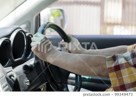 Hand of a senior male driver holding the steering wheel 99349473