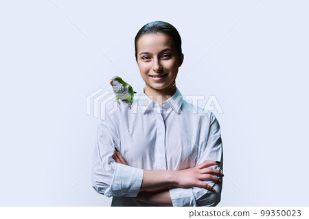 Young teenage female with green pet parrot, on white background 99350023