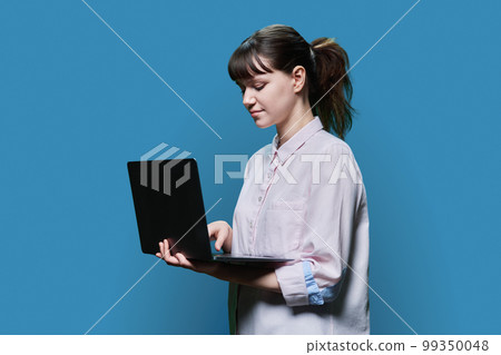 Serious female student looking at laptop screen, on blue background 99350048