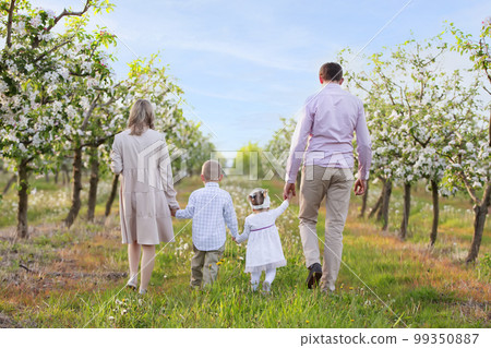 Happy family in a blooming garden.Mom dad and children go along the road of the spring garden. 99350887