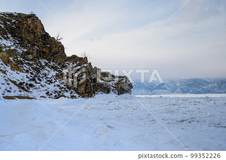 a raven is sitting on a pine tree. Lake Baikal. Winter Baikal. Small sea. ice and snow a raven is sitting on a pine tree. Lake Baikal. Winter Baikal. Small sea. ice and snow 99352226