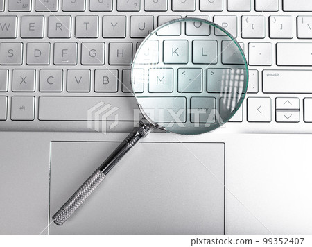 Magnifying lens over laptops keyboard. Seo and search concept Magnifying lens over laptops keyboard. Seo and search concept 99352407